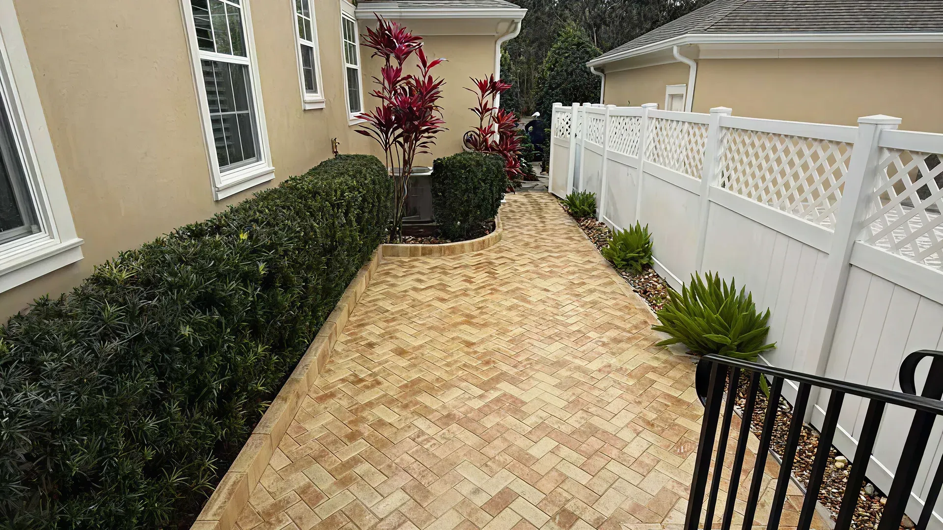 Homeowner cleaning a paver driveway using a brush and garden hose Homeowner cleaning a paver driveway using a brush and garden hose