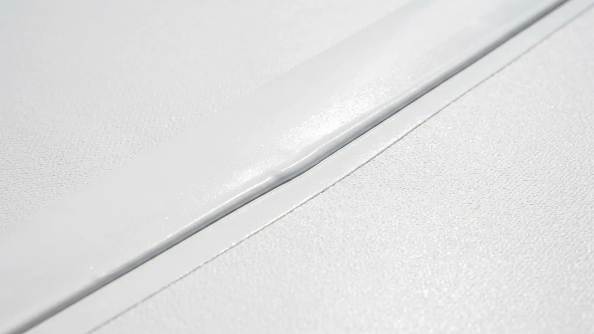 Close view of a heat-welded seam on a white single-ply roof membrane showing a clean, even seam edge