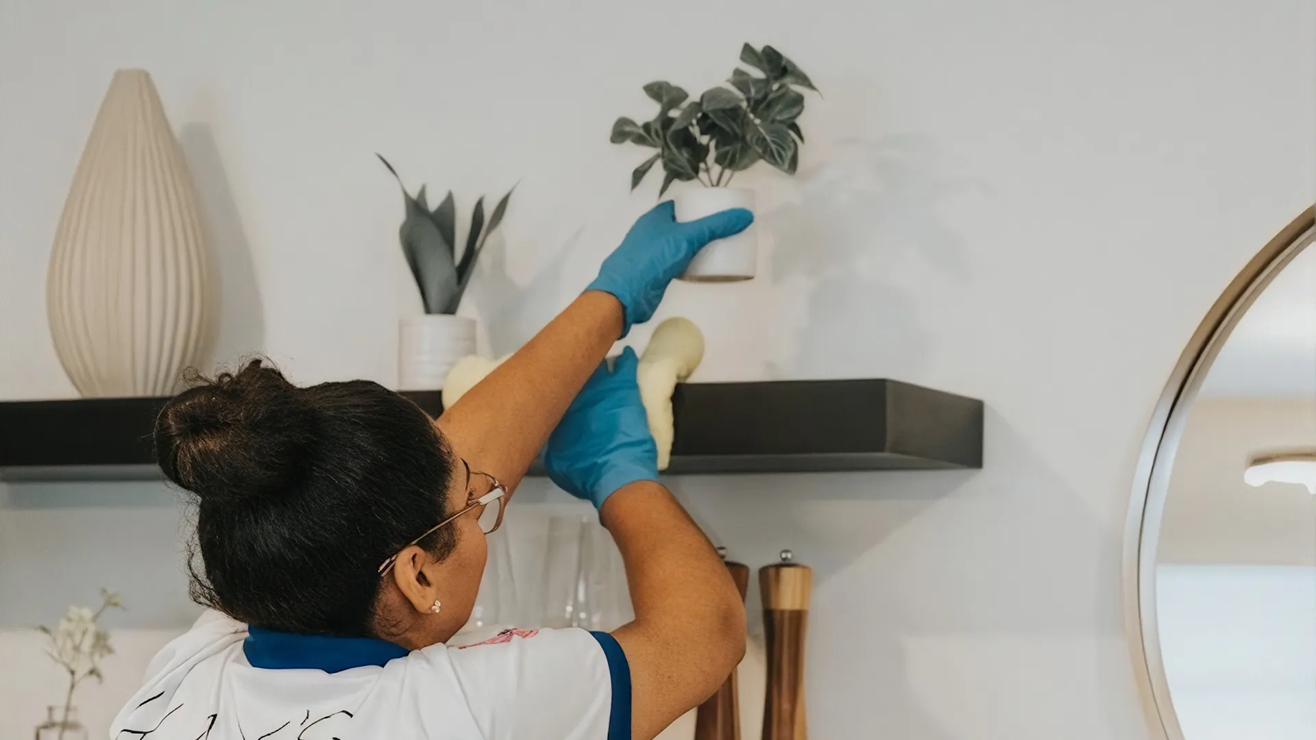 Kay's Cleaning Services professional dusting a living room shelf during a pre-Halloween cleaning refresh Kay's Cleaning Services professional dusting a living room shelf during a pre-Halloween cleaning refresh