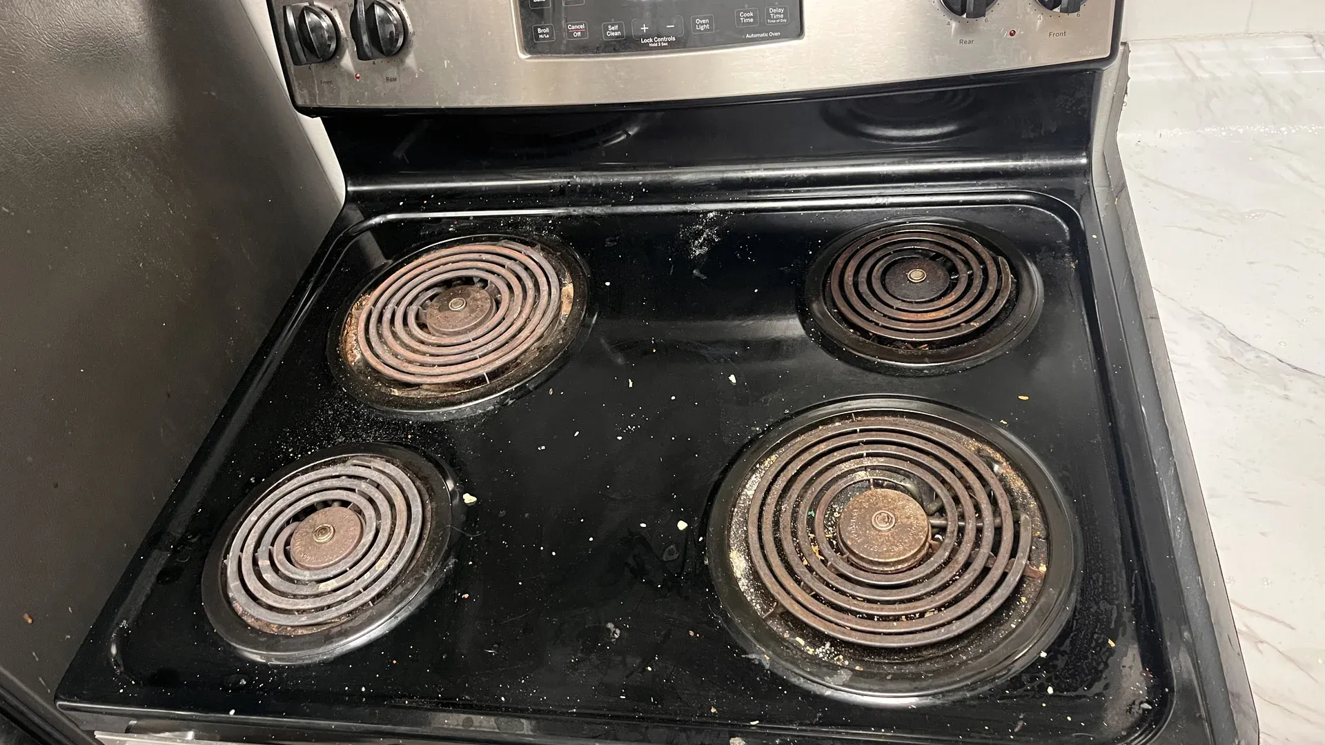 Greasy electric stovetop with burnt residue before a professional deep cleaning service in Tampa Bay