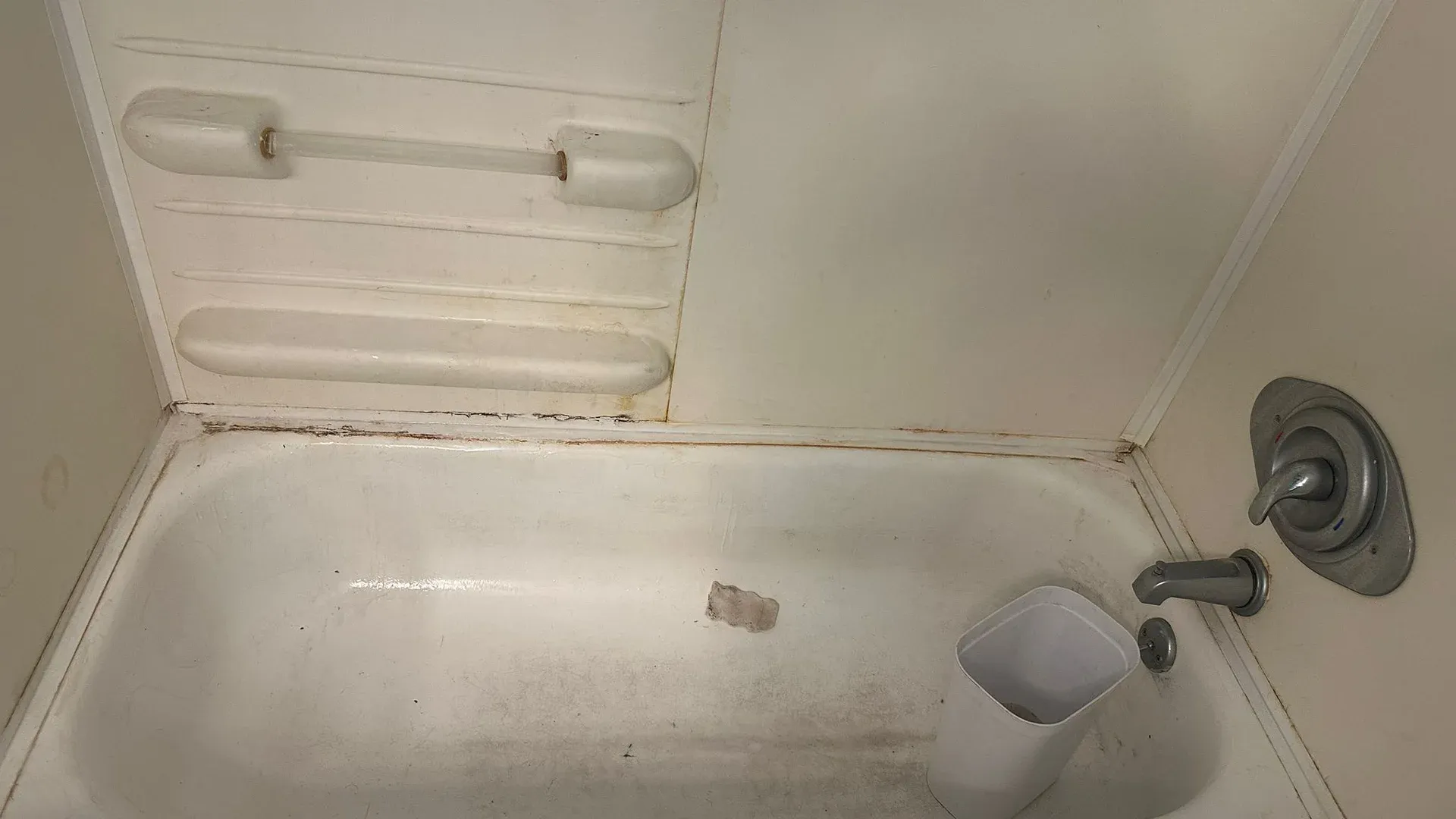 Stained bathtub with soap scum and debris that a deep cleaning service removes in a Tampa Bay home