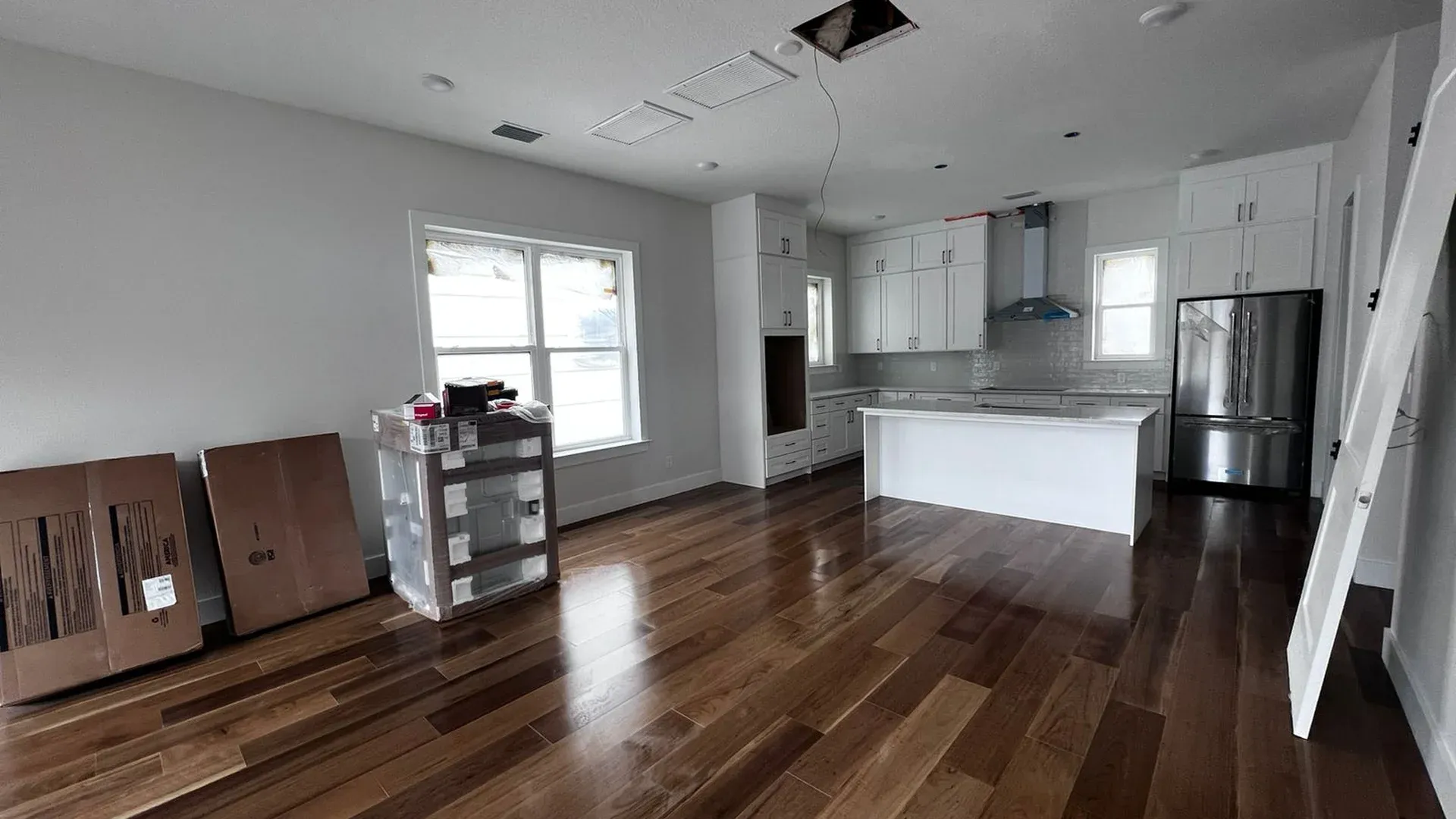 Empty open-plan kitchen and living area with hardwood floors waiting for post construction cleaning in Tampa Bay