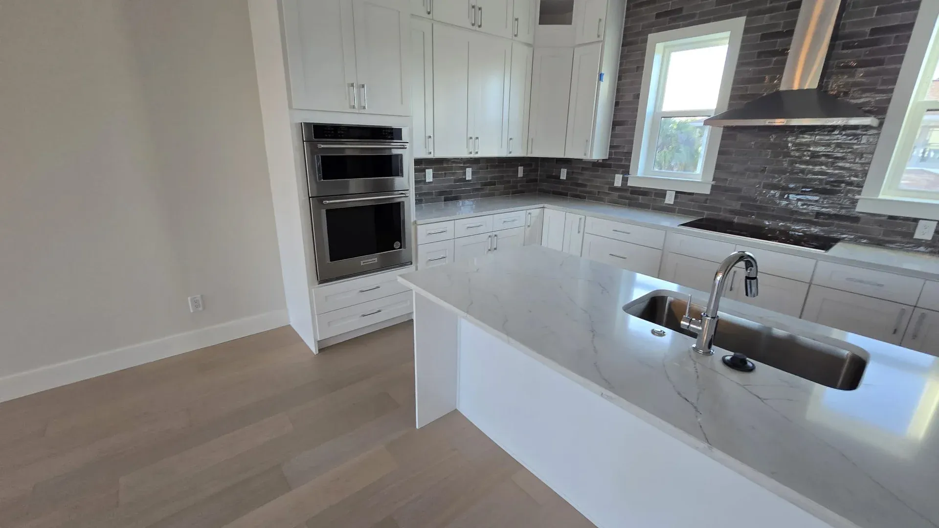 Newly renovated kitchen with white shaker cabinets and a quartz island ready for post construction cleaning