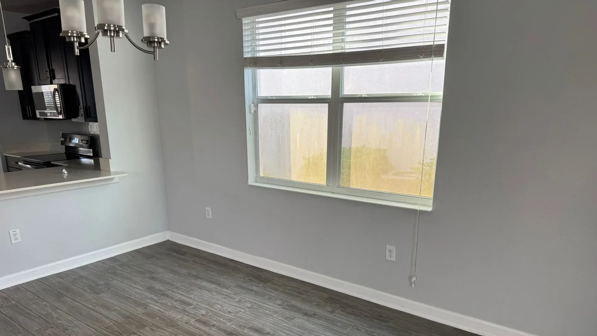 Empty finished room with gray walls, plank flooring and a window where fine construction dust settles