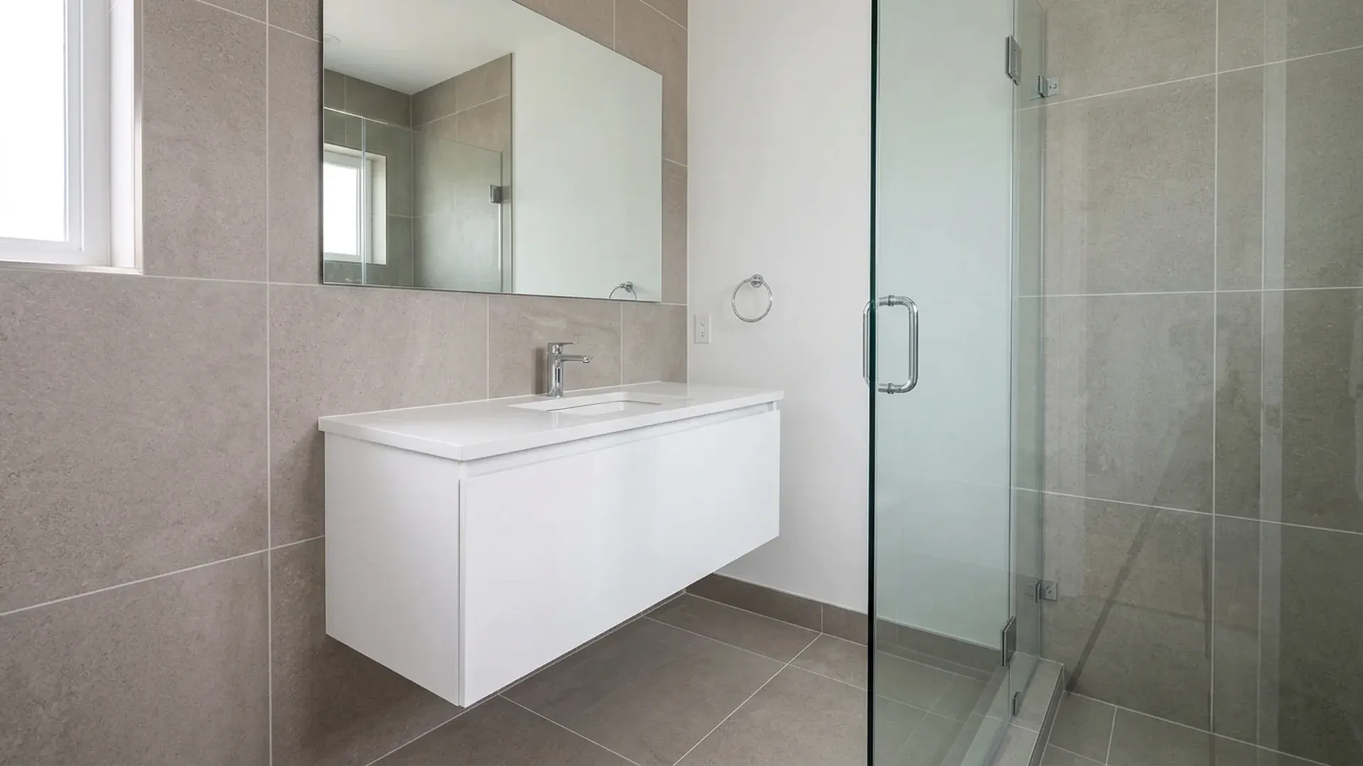 Clean renovated bathroom with large-format tile, floating vanity and frameless glass shower.